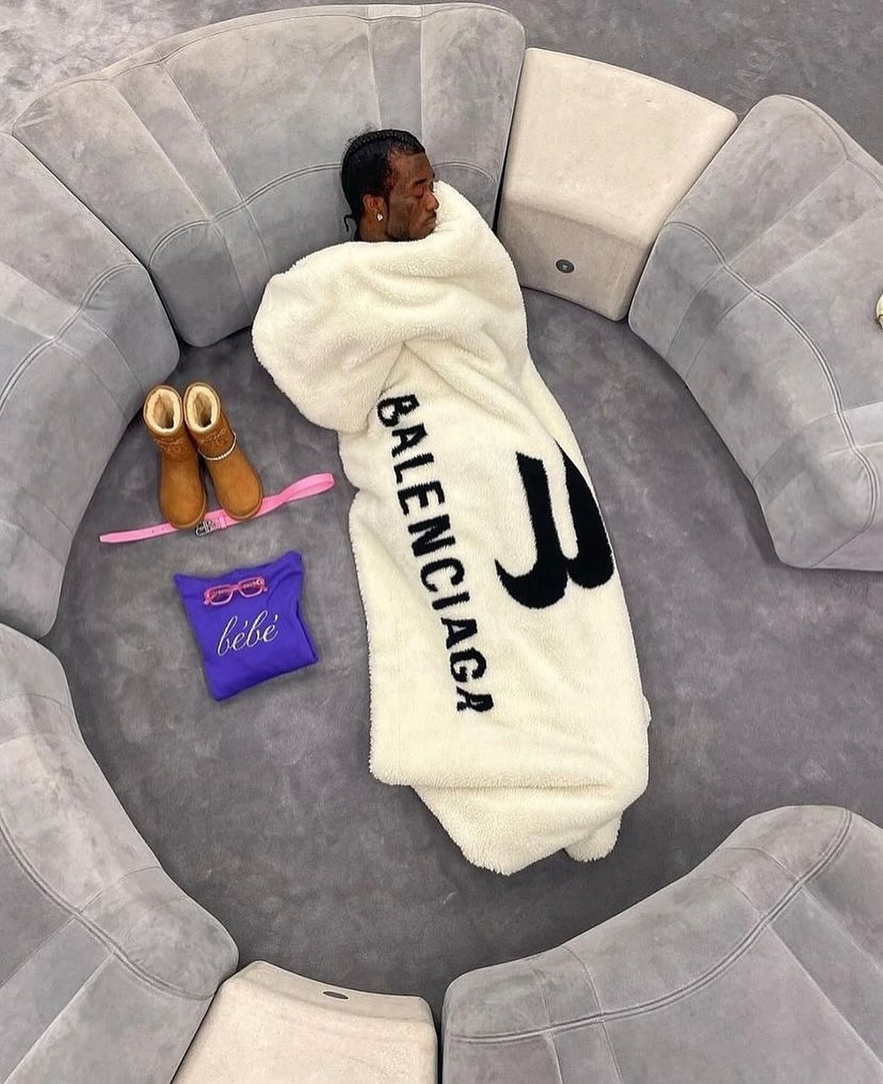 Lil Uzi Vert sitting among clothing racks and furniture inside a Balenciaga flagship store with exposed concrete walls