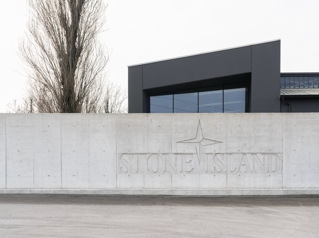 The renovated interior of Stone Island's Ravarino headquarters, known internally as The Lab, showing exposed concrete and industrial architecture.