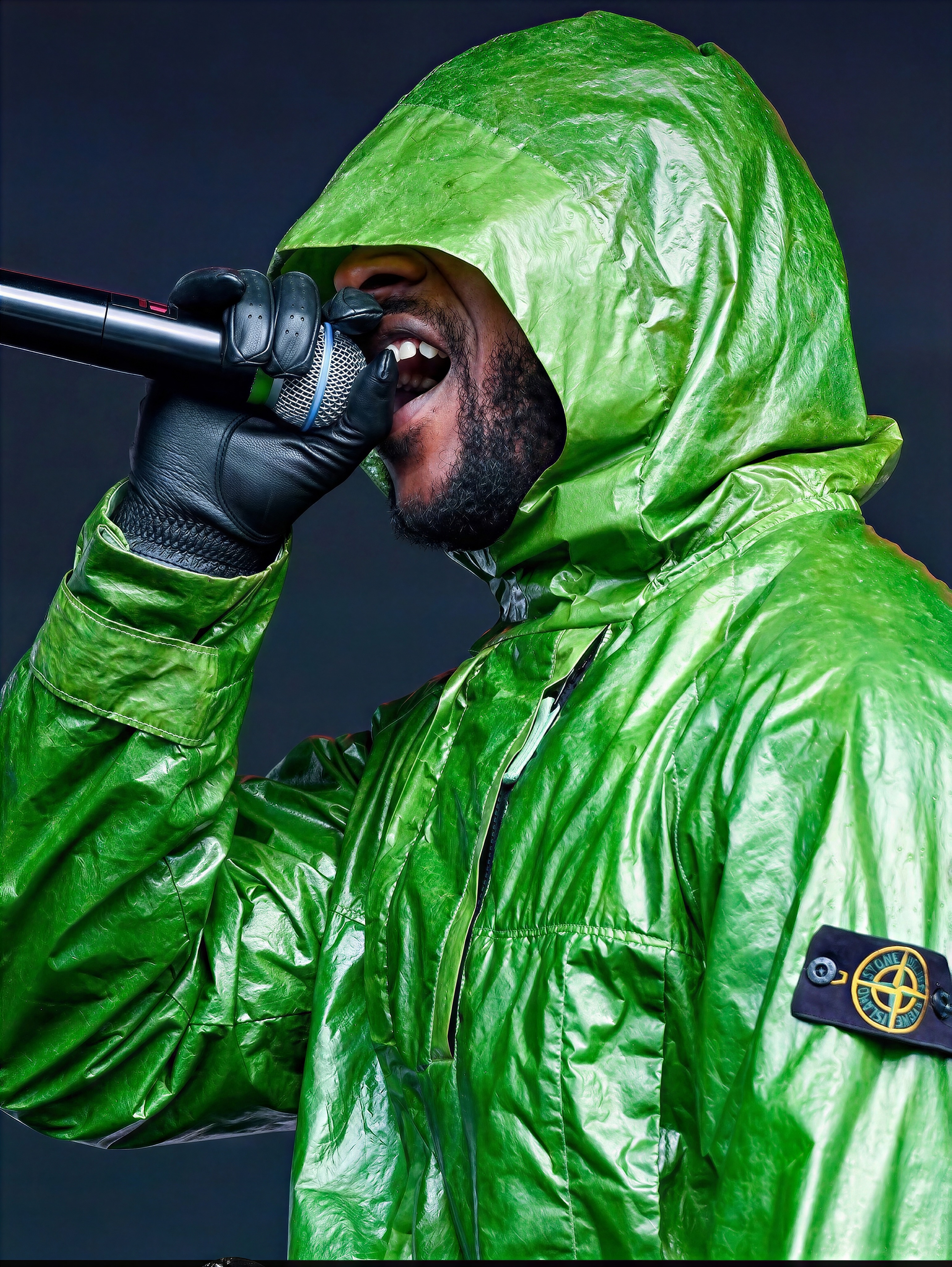 Skepta performing onstage at Reading Festival wearing a green Stone Island Micro Felt Transparent Cover Jacket