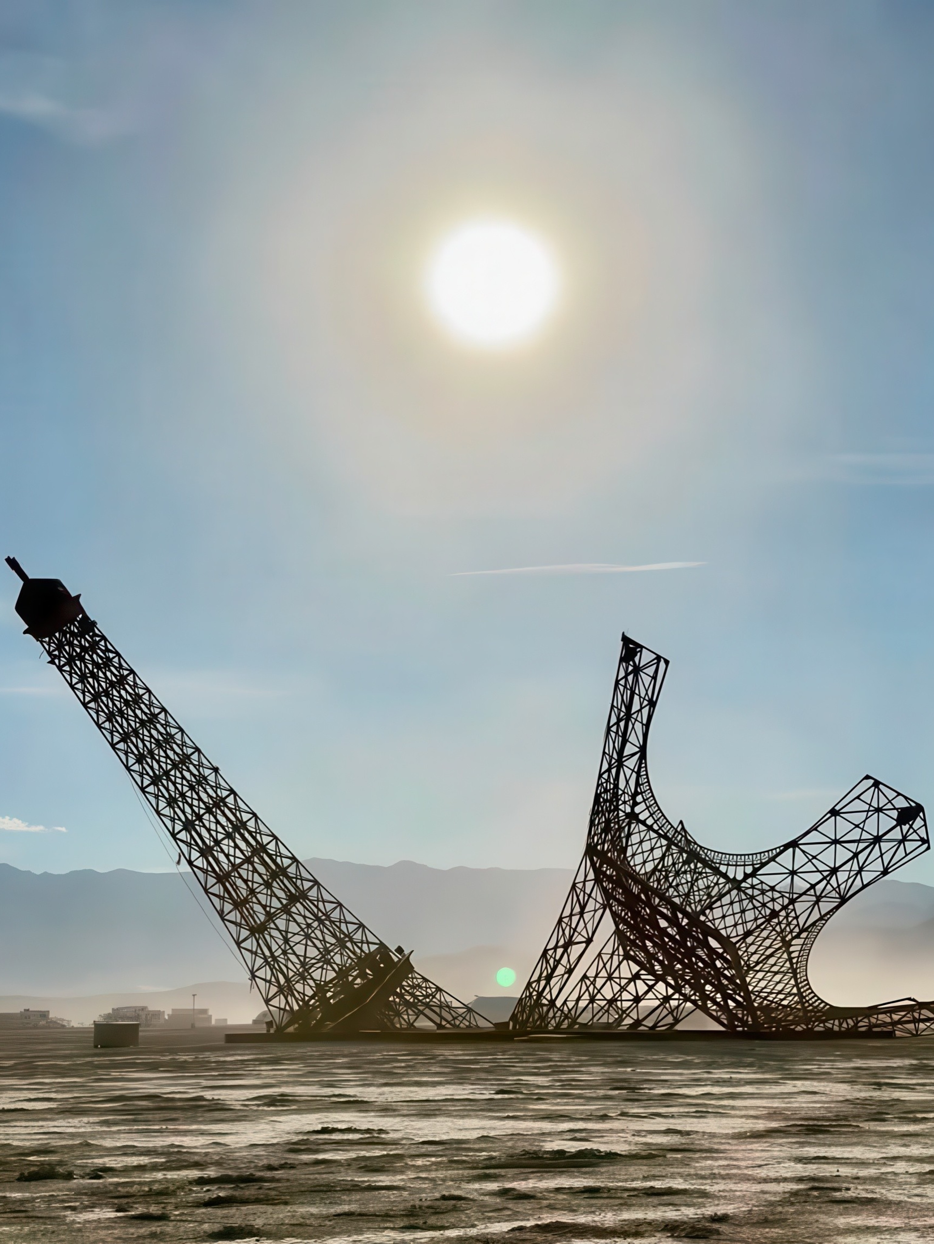 A broken steel replica of the Eiffel Tower, split into two halves, standing in the Nevada desert at Burning Man 2026.