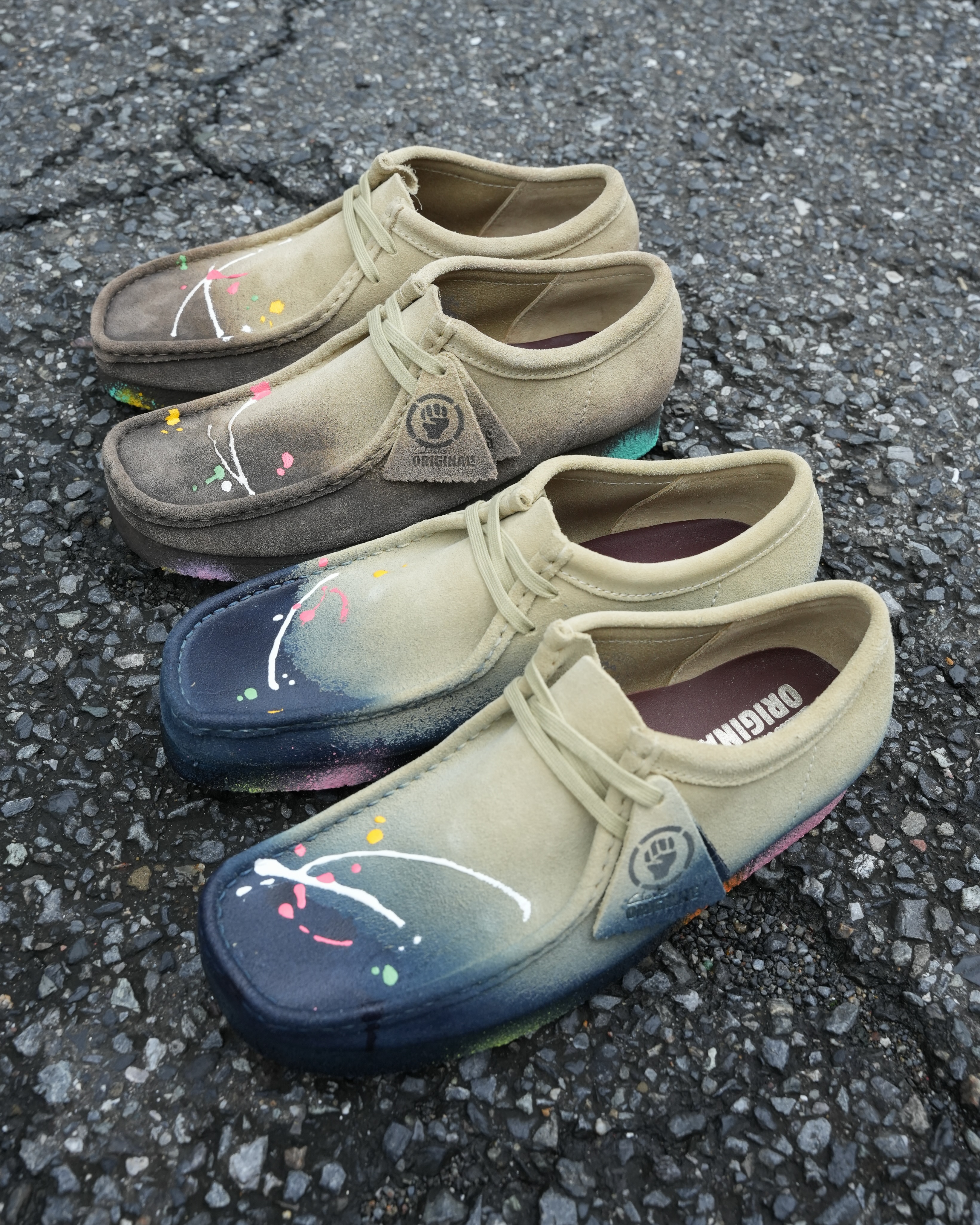 Two pairs of Clarks Wallabees with blue and brown grey dye, bright paint drips and pale suede collars.