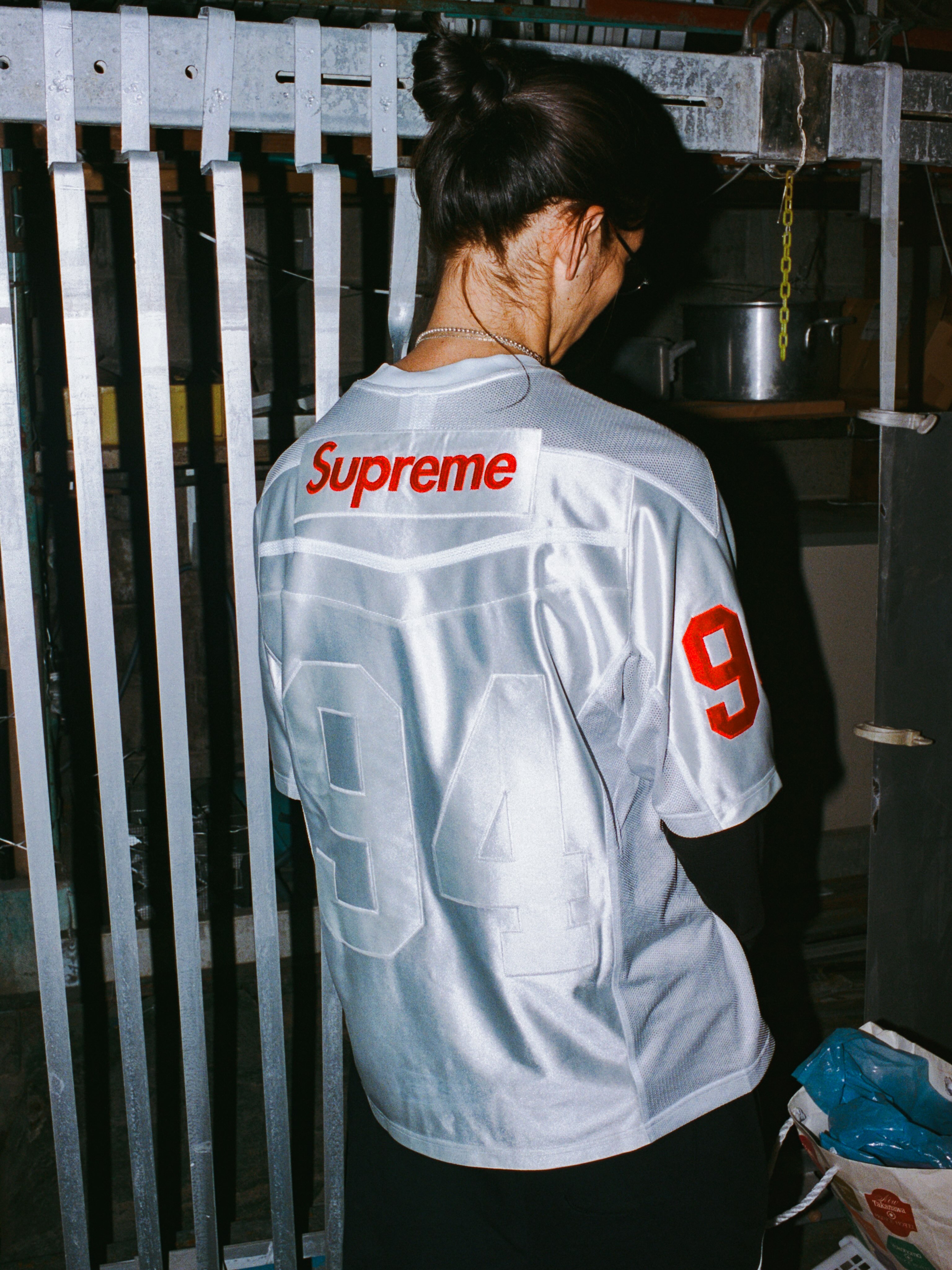 Model in a white Supreme and Nike hooded outfit with red panels, green piping and an oval Nike logo.