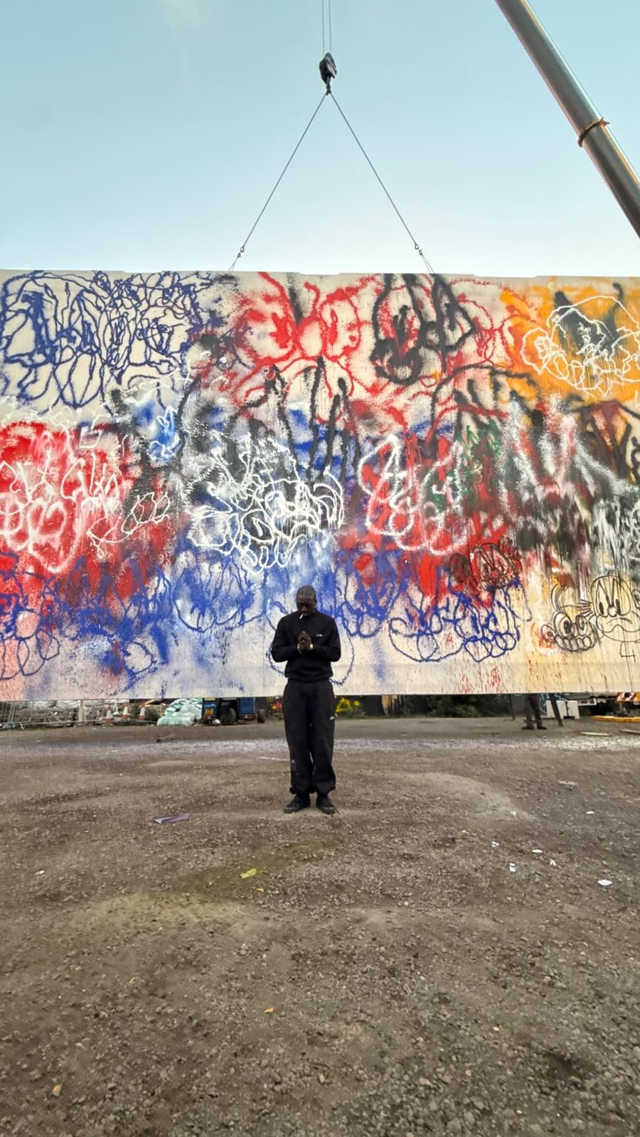 Slawn standing in front of his new painting, made while suspended from a crane in London.
