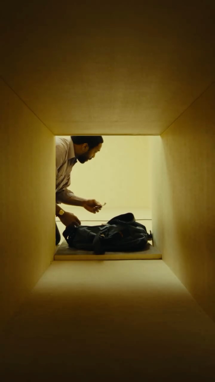 A promotional still from A24's theatrical rerelease of Backrooms, showing the film's yellow lit liminal interior setting.