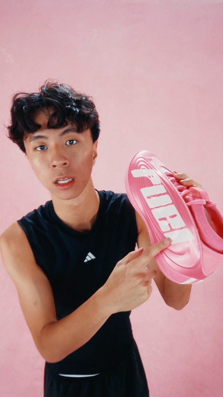 Ray holds a pink Adidas Harden shoe against a pink studio backdrop.