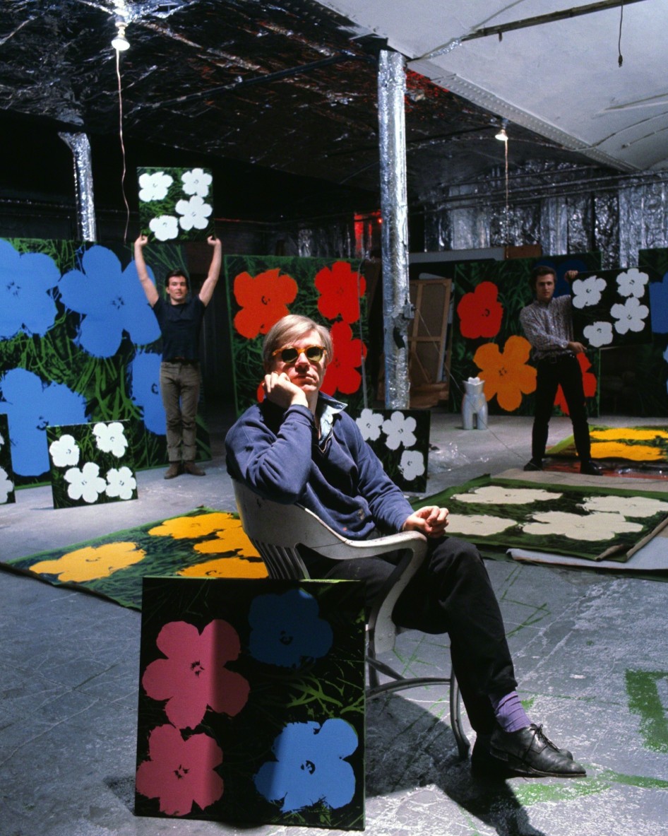 Andy Warhol photographed with Factory collaborators Gerard Malanga and Philip Fagan among his Flowers paintings, New York, 1964.