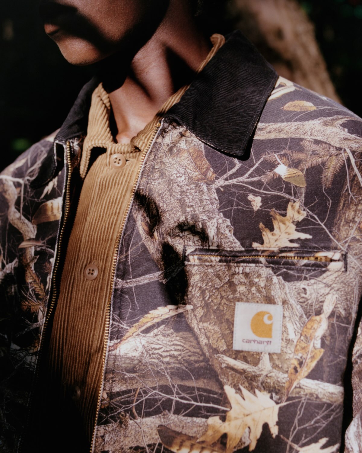 Carhartt WIP camo feather tree print jacket in a stone washed black finish