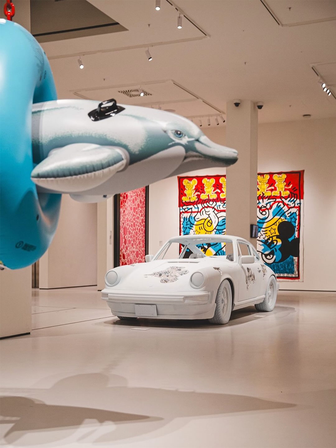 Daniel Arsham’s pale eroded Porsche sculpture beside a curved staircase at Moco London.