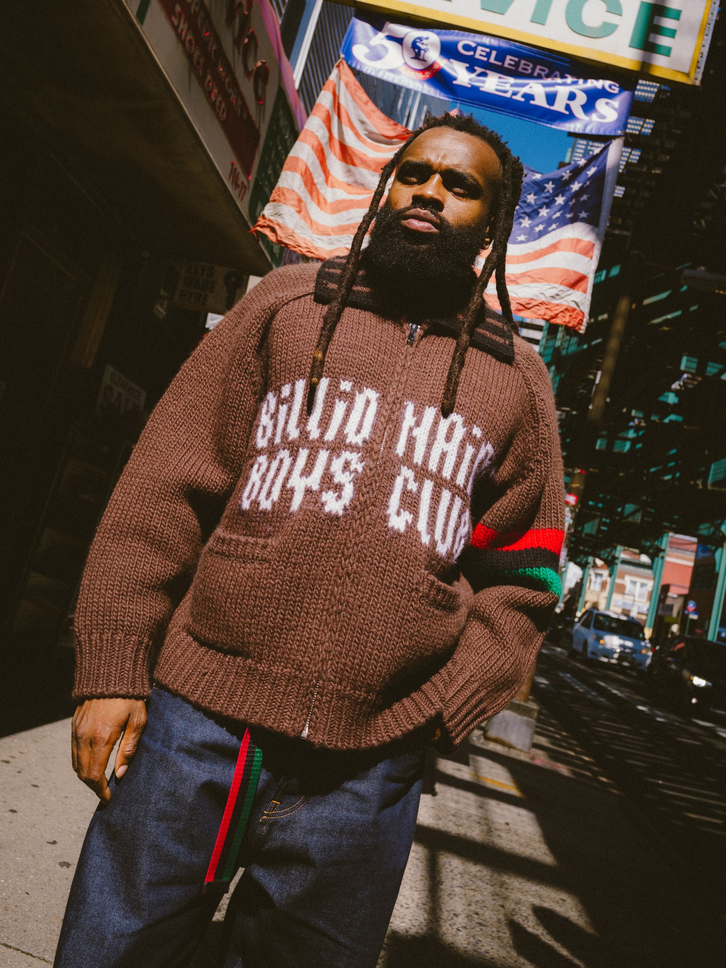 A model wears a brown BBC knit with red and green stripes and dark striped trousers.