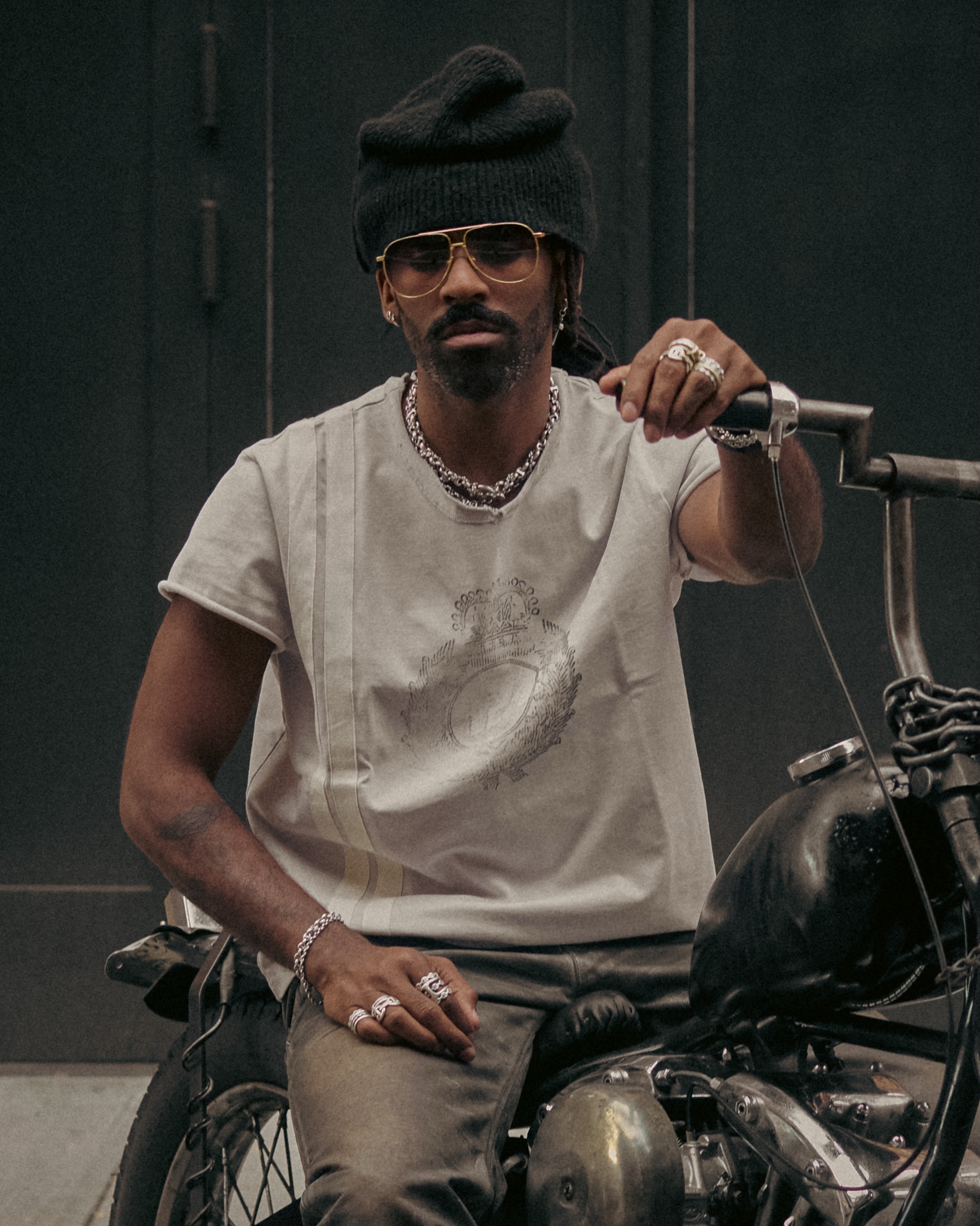 Justin Boone wears gold coloured DITA 424 ARTOA.92 glasses beside a red motorcycle helmet.