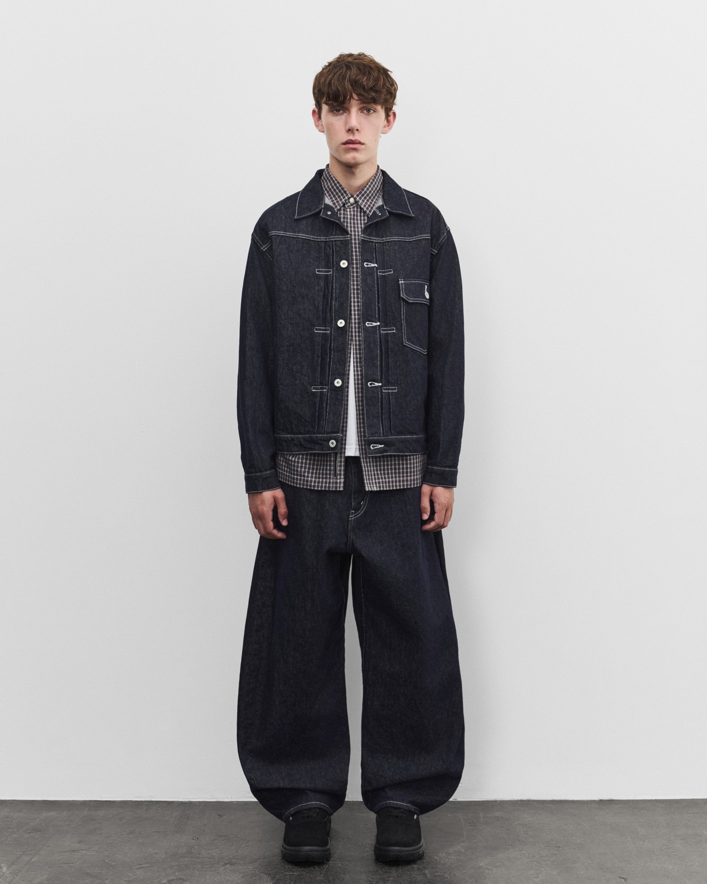 Comme des Garçons Homme FW26 garments on display at Dover Street Market New York, showing multi fabric patchwork jackets mixing nylon, wool, and leather panels.