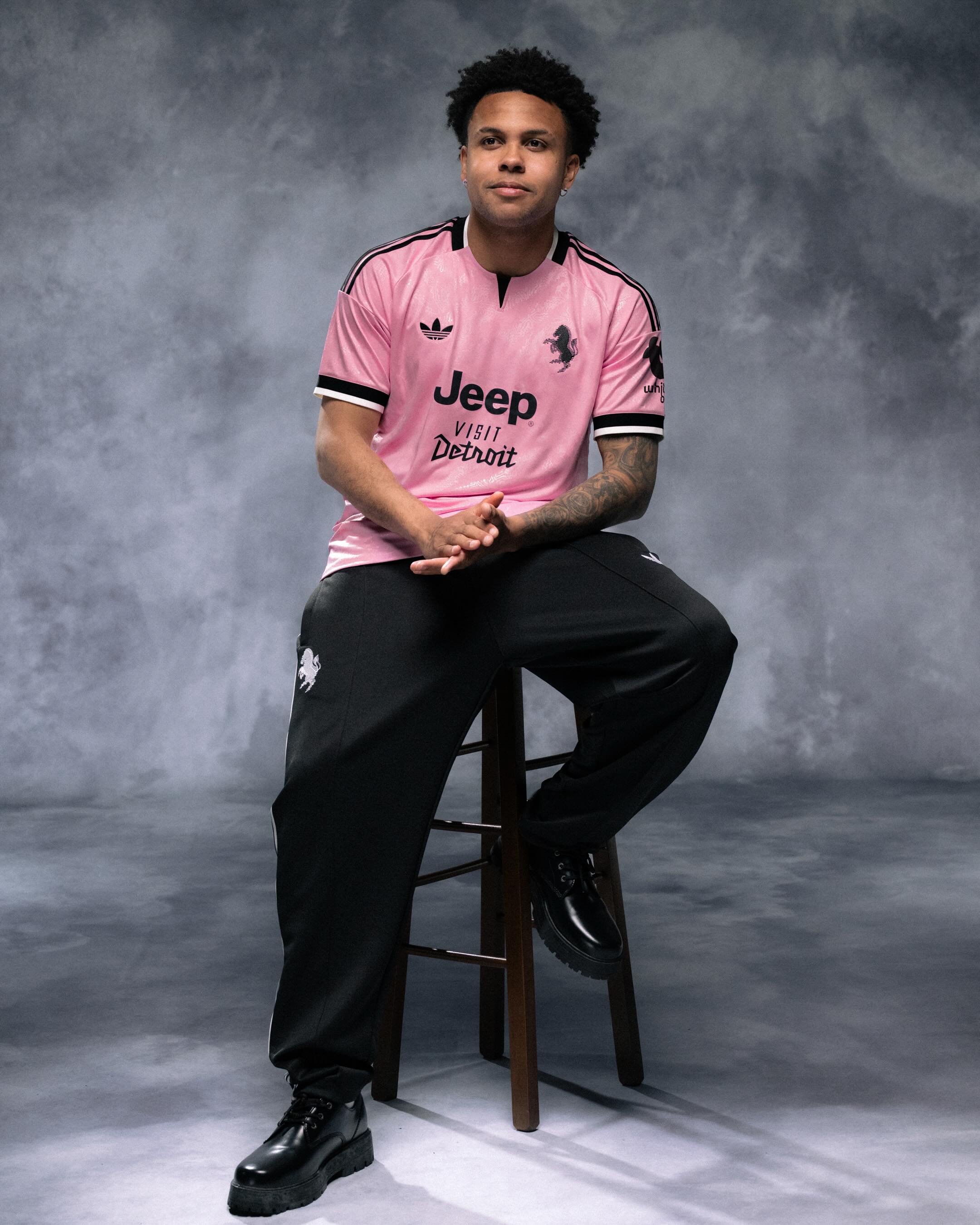 A pink Juventus away jersey with a tonal zebra pattern and black trim on the collar, cuffs and shoulders, displayed against a plain background.