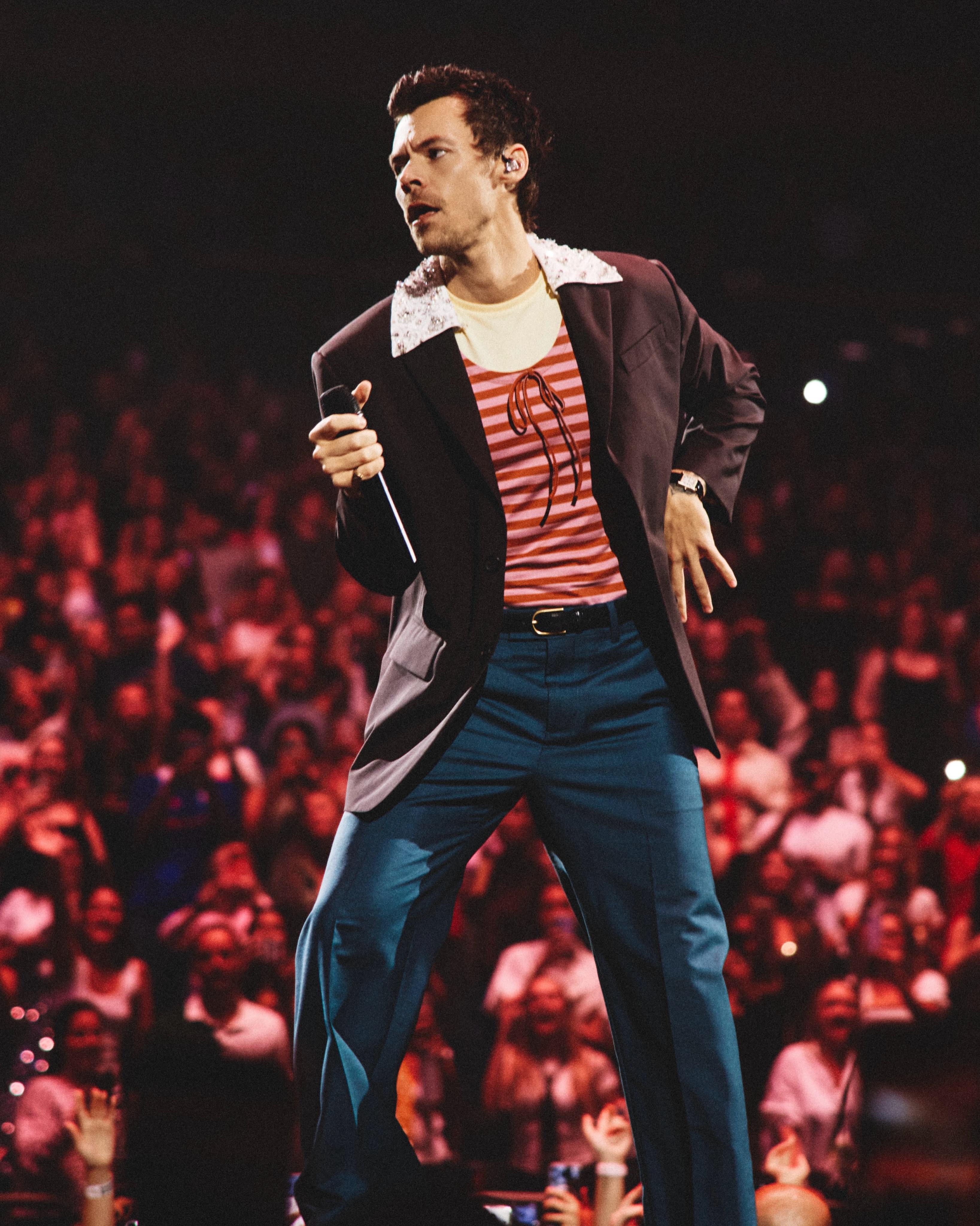 Harry Styles wearing a custom Miu Miu plum kid mohair blazer and powder blue trousers on stage.