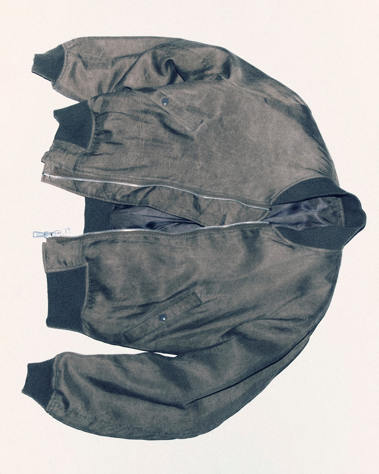 Our Legacy’s Marsh Khaki bomber shows a mottled cupro surface and dark ribbed edges.