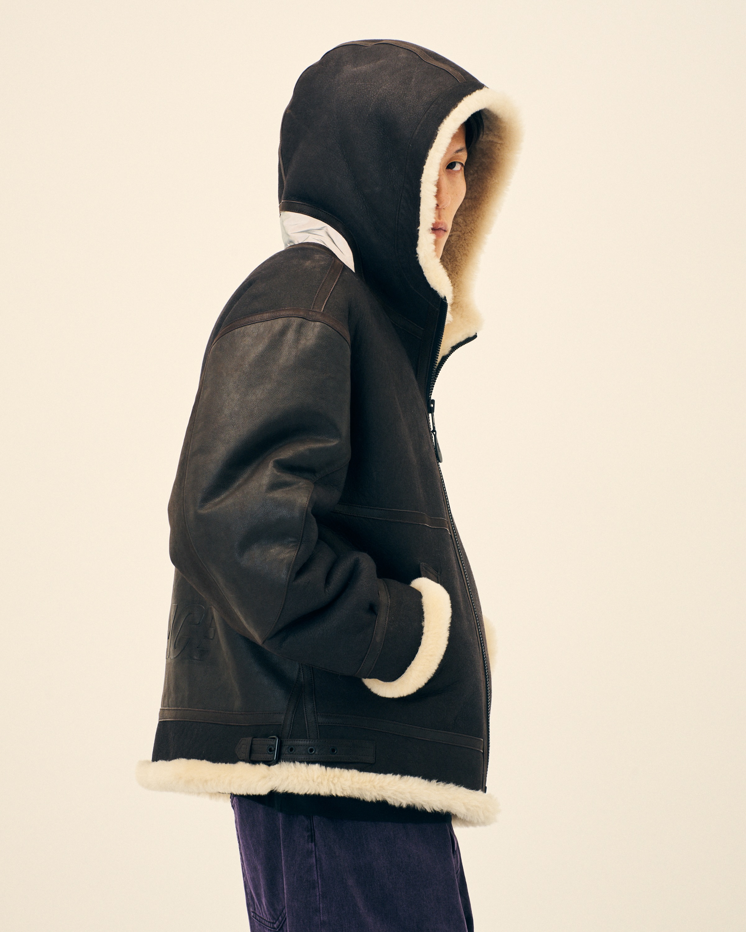 A Palace model wears a dark hooded jacket with pale lining.