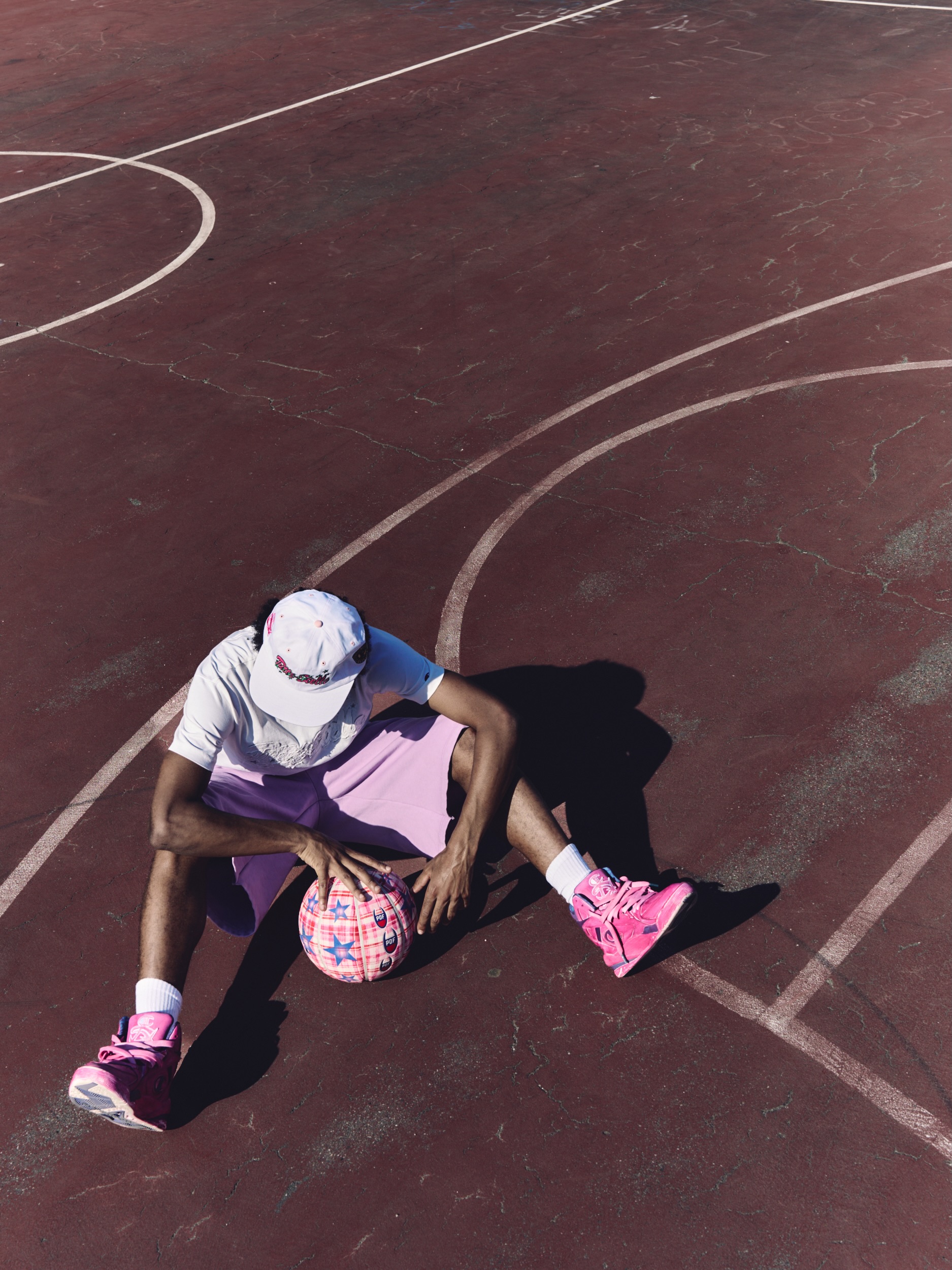 A model wears the beige nylon PDF X Champion Campione Mondiale full zip track top with an allover star print, holding a red PDF X Champion basketball.