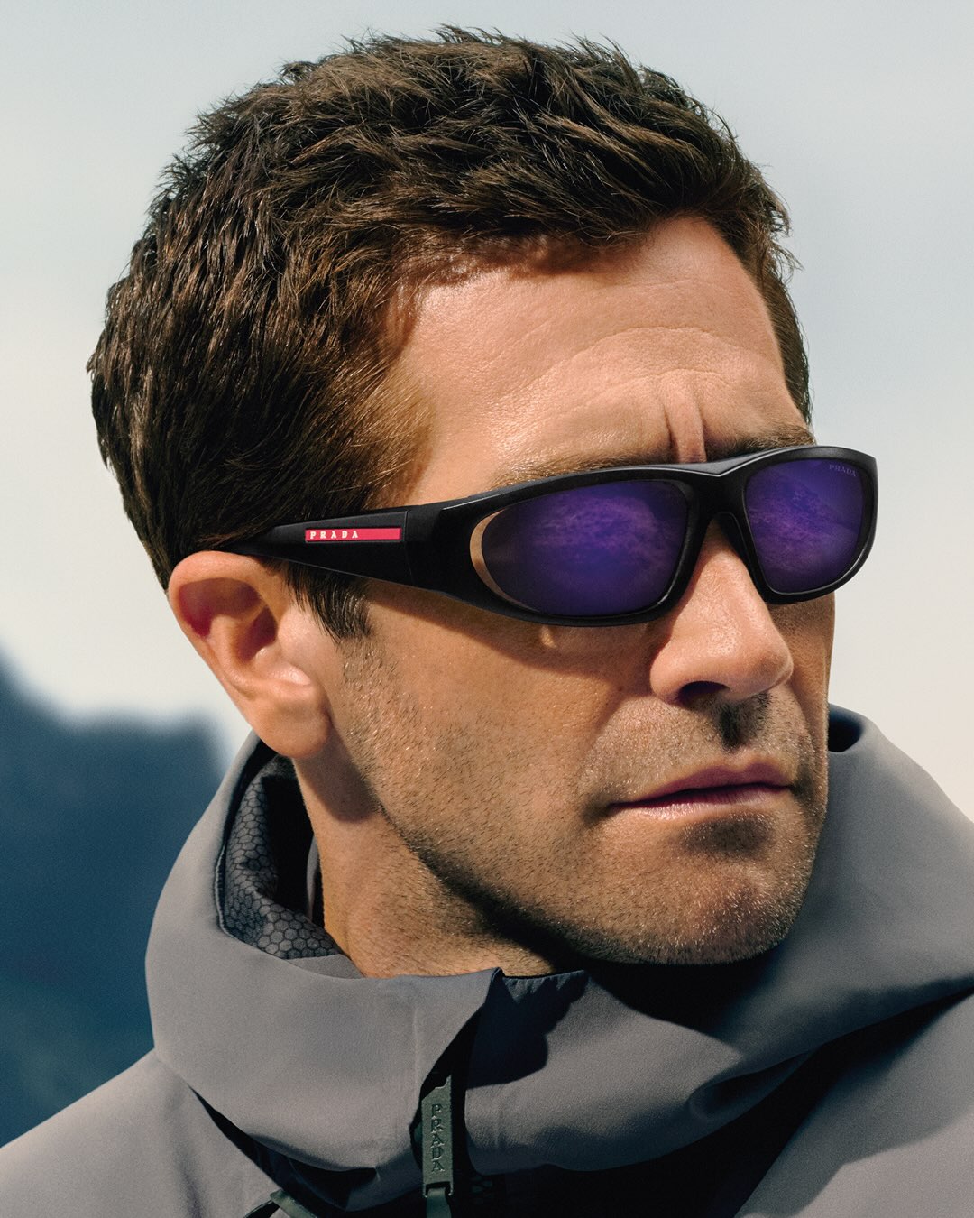 Jake Gyllenhaal photographed on an icy landscape wearing Prada Linea Rossa eyewear for the New Heights campaign.