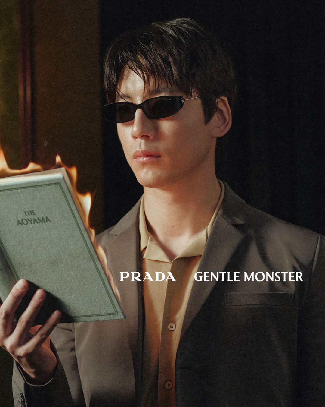 A titanium Prada Gentle Monster eyewear frame with the Prada Triangle logo set sideways across the front.