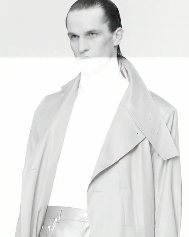 Product photo of a boxy black Rick Owens trench coat in organic cotton styled with strapped platform boots.