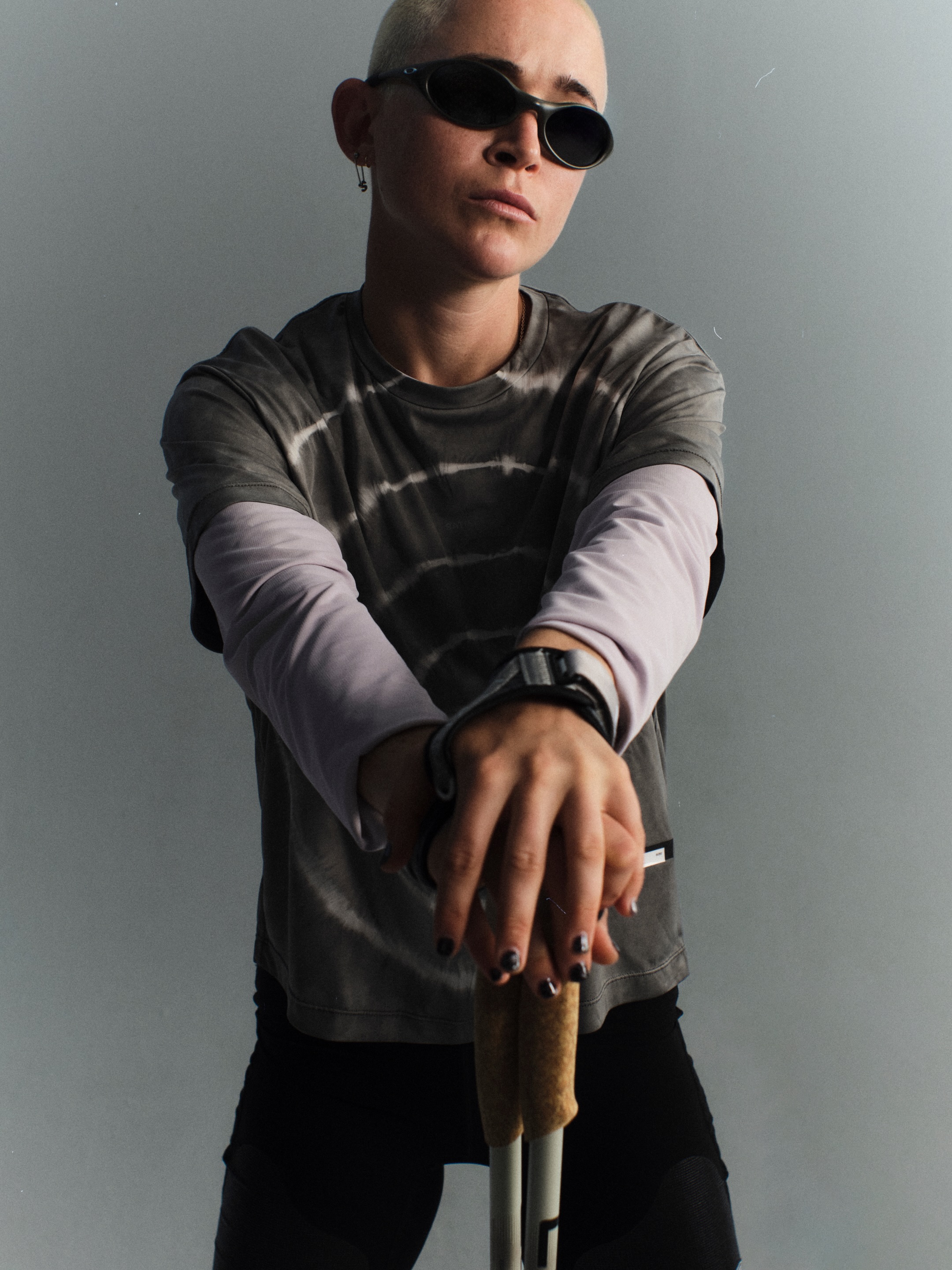 Molly Seidel wears a grey spiral Satisfy tee over lilac sleeves and holds trekking poles.