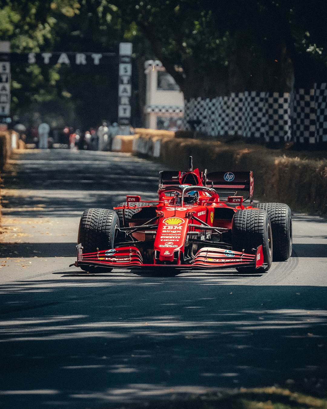 A Ferrari running the Goodwood Festival of Speed hillclimb course lined with hay bale barriers