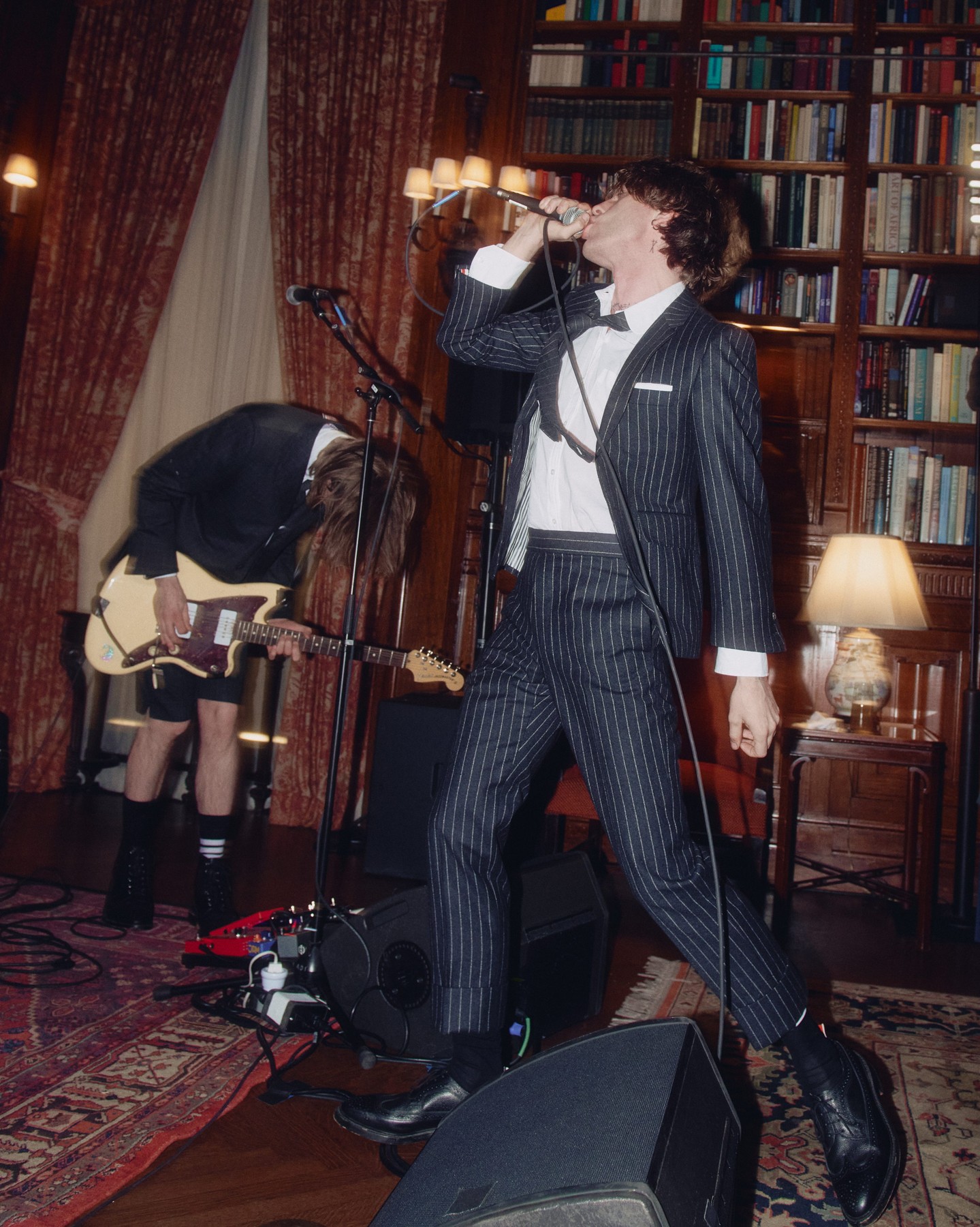 Iceage performs among bookshelves at Thom Browne’s Lotos Club event.