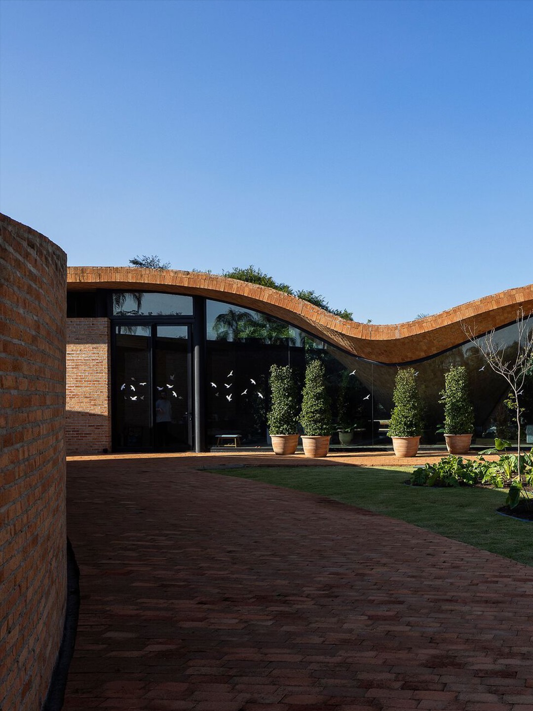 The Passive House by Mareines Arquitetura, showing its curved brick roof and walled triangular garden in São Paulo state, Brazil.