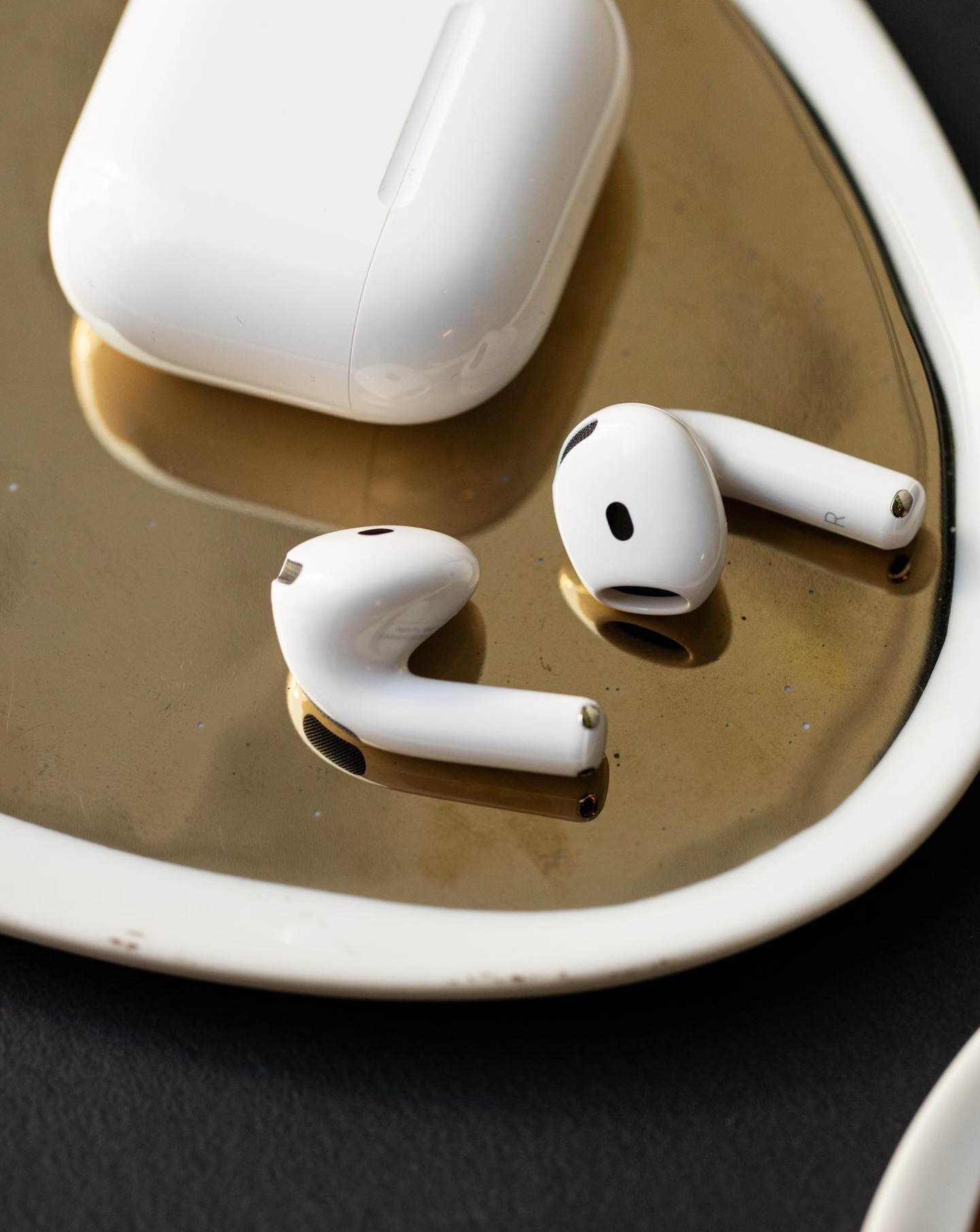 Apple AirPods 5 earbuds and charging case shown in the open ear design without silicone tips.