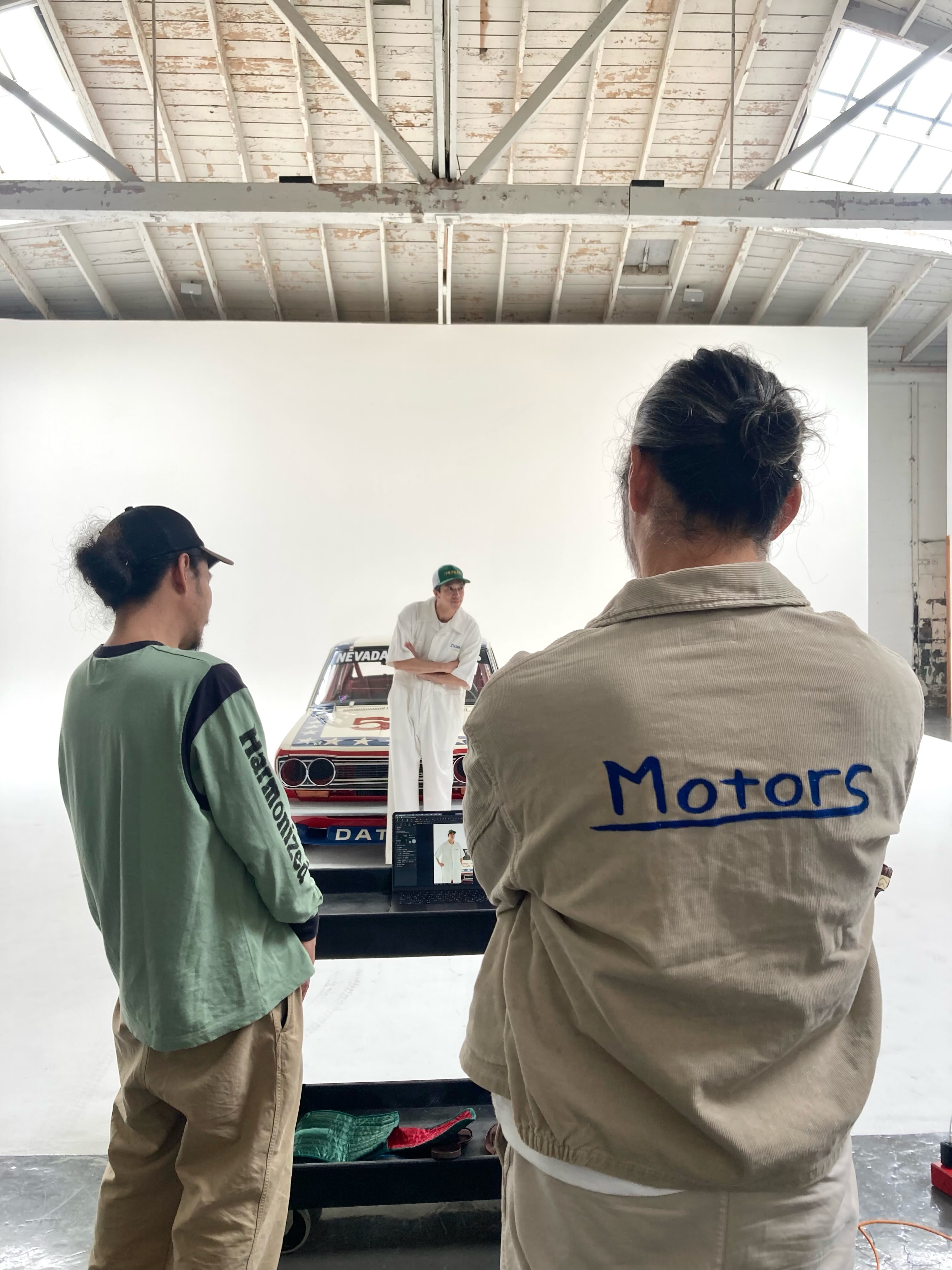 Promotional image for WMV's VISVIM MOTORS CLUB 2026 lookbook shoot, the capsule visvim builds around vintage car and motorcycle driving gear.