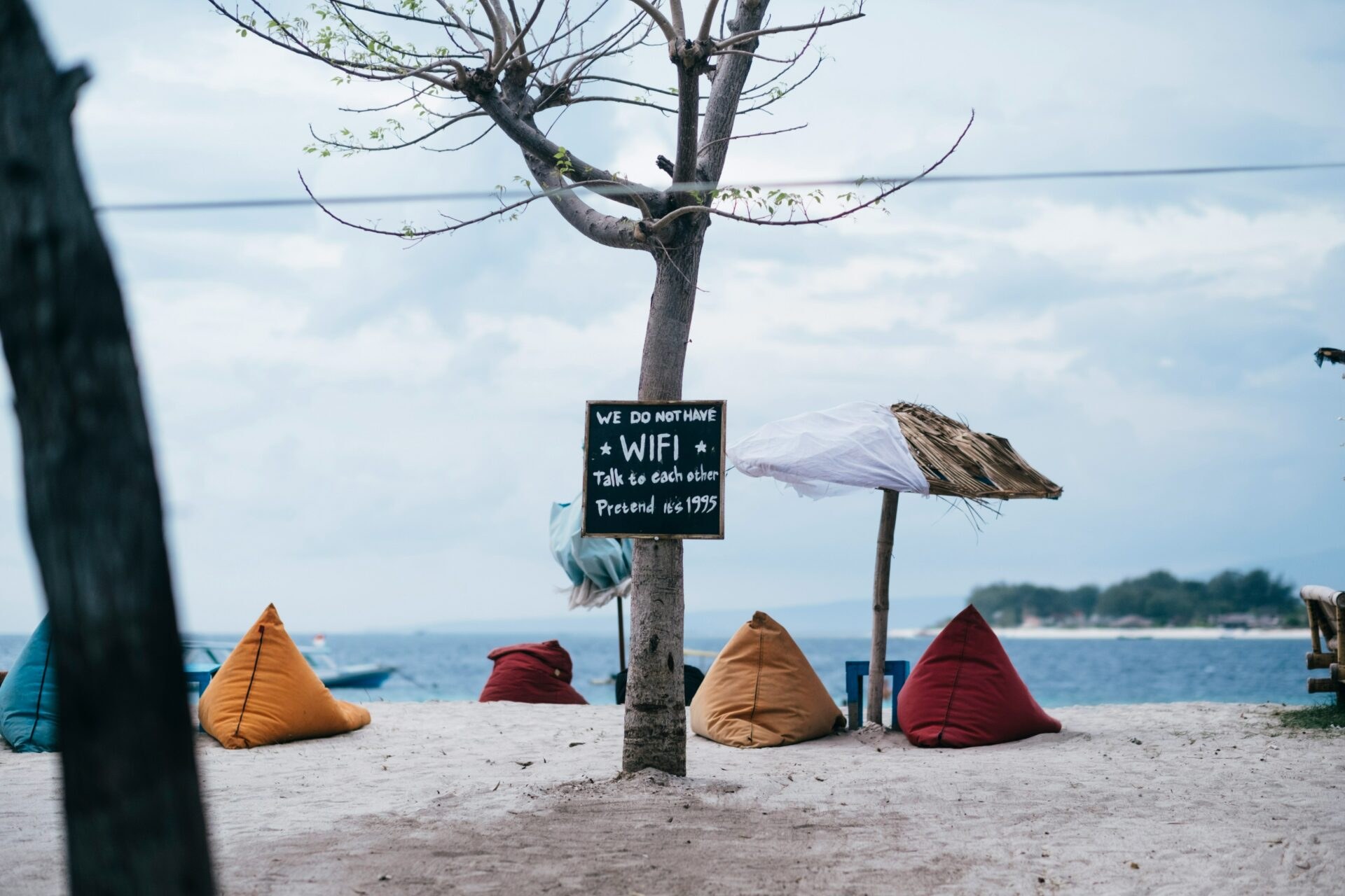 A hand painted beach sign that reads we do not have WiFi, talk to each other, pretend it's 1995