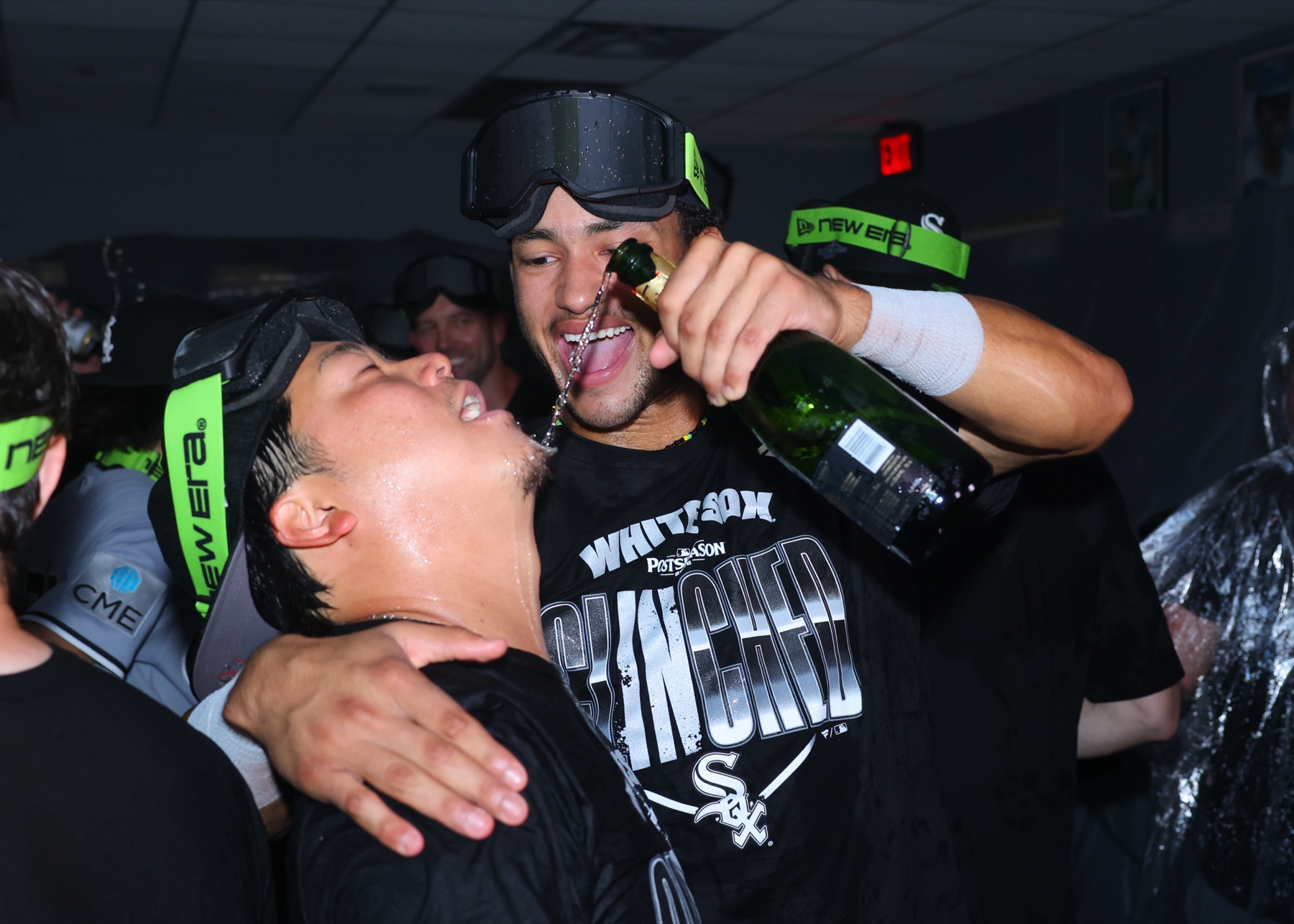 Chicago White Sox players in postseason clinched shirts and goggles spraying champagne in the clubhouse