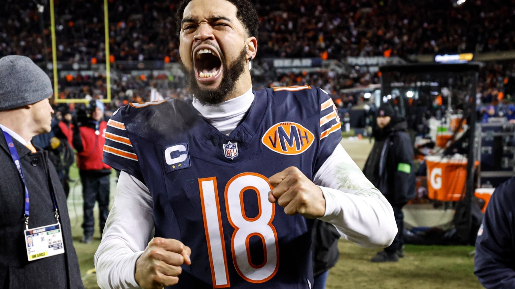 Chicago Bears quarterback Caleb Williams celebrating on the sideline, fists clenched, wearing jersey number 18